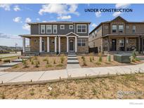 New two-story home with stone accents, covered porch, and landscaping under construction at 9857 Biscay St, Commerce City, CO 80022