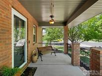 Inviting covered front porch with brick pillars, black metal railings and a bench to enjoy the outdoors at 101 Se 2Nd St, Berthoud, CO 80513