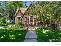 Charming brick home features a tile roof, arched entry, and inviting front porch with lush landscaping at 1035 Spruce St, Boulder, CO 80302