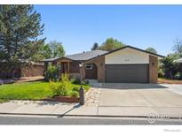 Charming single-story home with a well-manicured lawn, stone walkway and a two-car garage at 1610 Vivian St, Longmont, CO 80501