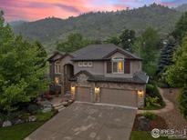 Beautiful two-story home featuring a stone facade, three-car garage, and lush landscaping against a scenic mountain backdrop at 19061 Eagle Ridge Dr, Golden, CO 80401