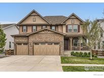 Charming home with a three-car garage, stone accents, covered porch and mature tree at 2165 Summerlin Ln, Longmont, CO 80503