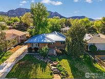 Charming brick home featuring a blue metal roof, professional landscaping, and mountain views at 325 Colgate St, Boulder, CO 80305