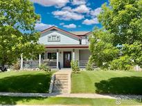 Charming two-story home with a covered front porch and beautifully landscaped front yard at 395 Longspur Dr, Brighton, CO 80601