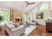 Bright living room features a stone fireplace, wood floors, and large windows at 4924 Clubhouse Ct, Boulder, CO 80301
