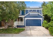 Charming two-story home with a blue facade, well-manicured lawn, and solar panels on the roof at 911 Homer Cir, Lafayette, CO 80026