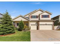 Charming two-story home with a three-car garage, well-maintained lawn, and mature landscaping at 10278 Dover St, Firestone, CO 80504