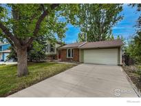 Charming single-Gathering home with a well-maintained lawn, mature trees, and a long driveway leading to a two-car garage at 117 Sandler Dr, Lafayette, CO 80026