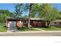 Charming single-story brick home with a well-manicured lawn, mature trees, and a driveway leading to an attached garage at 1204 Sherri Mar Ct, Longmont, CO 80501