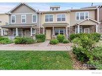 Charming townhome featuring stone accents, a covered porch, and manicured landscaping at 13624 Garfield St # B, Thornton, CO 80602