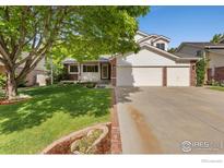 Charming two-story home featuring a well-manicured lawn, mature trees, and a two-car garage at 2421 Maplewood W Cir, Longmont, CO 80503