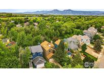 Picturesque aerial view of a neighborhood with mature trees, green grass, and mountain views at 4489 Wellington Rd, Boulder, CO 80301