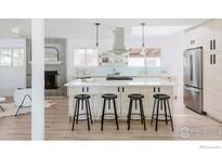 Modern kitchen featuring a large island with seating, sleek appliances, and a stylish vent hood at 4601 S Lipan St, Englewood, CO 80110