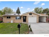 Charming brick home featuring solar panels, a well-maintained lawn, and an attached one car garage at 5329 Flower Cir, Arvada, CO 80002