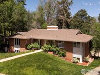 Charming single-story brick home featuring a manicured lawn, mature trees, and a welcoming front entrance at 1035 Rosehill Dr, Boulder, CO 80302