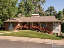 Charming single-story brick home with lush landscaping, red rose bushes, and a cozy, covered porch at 1035 Rosehill Dr, Boulder, CO 80302