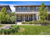 Charming townhome featuring a covered porch and beautifully landscaped front yard with benches for relaxing at 11033 E 28Th Pl, Denver, CO 80238