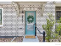 Charming brick home featuring a blue front door with glass and a decorative wreath and a Welcome mat at 12155 W 57Th Pl, Arvada, CO 80002