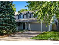 Charming two-story home with a well-maintained front yard, mature trees, and an attached two-car garage at 1359 Caledonia Cir, Louisville, CO 80027