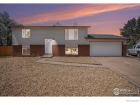 Exterior view of a two-story home with vinyl siding, brick accents, gravel landscaping, and a two car garage at 15904 E Bates Pl, Aurora, CO 80013