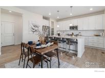 Bright eat-in kitchen boasts white cabinets, stainless appliances, and a dining table at 1953 Morgan Dr, Erie, CO 80516