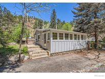Cozy cabin-style home with stone foundation, sunroom, and large lot with mature trees at 29 Silver Spruce, Boulder, CO 80302