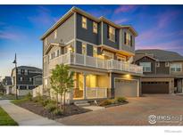 Beautiful two-story home featuring a two-car garage and charming wrap-around porch with white railing at 542 Highlands Cir, Erie, CO 80516