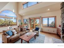 Bright living room featuring hardwood floors, a large arched window, and sliding door access to deck at 84 Canon View Rd, Boulder, CO 80302