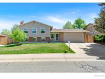 Charming two-story home featuring a well-manicured lawn, brick accents, and an attached two-car garage at 8963 W 75Th Cir, Arvada, CO 80005
