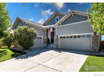 Charming gray home with well-manicured lawn, stone accents, and a spacious three-car garage at 102 Ortega Ct, Erie, CO 80516