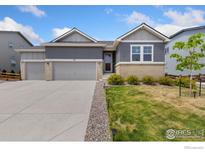 Inviting home featuring a three-car garage, gray siding, brick accents and well-maintained landscaping at 113 Marlowe Dr, Erie, CO 80516