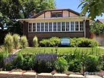Charming brick home featuring a landscaped front yard with an array of flourishing flowers and a 