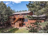 View of a multi-story house surrounded by trees, showcasing a large deck with stairs at 133 Mine Ln, Boulder, CO 80302