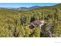 Stunning aerial view of a home nestled in a lush forest setting with mountain views at 141 Millionaire W Dr, Boulder, CO 80302