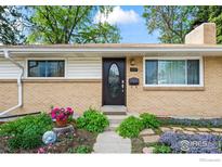 Charming front door with decorative glass and brick accents, surrounded by lush landscaping at 1880 E 84Th Ave, Denver, CO 80229