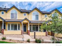 Inviting townhome featuring a bright yellow facade, charming porch, and a well-maintained front yard at 2855 Rock Creek Cir # 200, Superior, CO 80027
