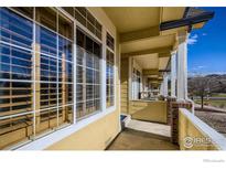 Exterior view of a covered porch with brick pillars and large windows, showcasing the home's facade at 2855 Rock Creek Cir # 200, Superior, CO 80027