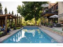 Beautiful pool with a pergola covered lounge area, and an outdoor fireplace on the upper balcony, perfect for relaxing at 3737 Spring Valley Rd, Boulder, CO 80304