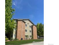Well-maintained apartment building with brick accents and lush green landscaping on a beautiful day at 50 19Th Ave # 9, Longmont, CO 80501