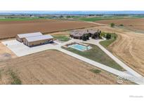 Expansive estate featuring a custom home, large shop buildings, and outdoor basketball court amidst picturesque farmland at 5454 County Road 38, Platteville, CO 80651