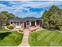 Beautiful brick home with manicured lawn, fountain, and mature trees creates an inviting curb appeal at 13 Blue Heron Dr, Thornton, CO 80241