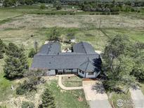 Expansive aerial view of a ranch-style home with an attached garage nestled on a sprawling, green, fenced lot at 1428 S County Road 23E, Berthoud, CO 80513