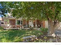 Charming brick home with a covered front porch and a lush, landscaped yard at 1513 Elmhurst Dr, Longmont, CO 80503