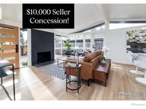 Bright living room features a black brick fireplace, light hardwood floors, and multiple glass doors to the outdoor area at 2435 S Meade St, Denver, CO 80219