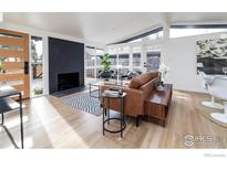 Bright living room featuring a modern fireplace, stylish furniture, and ample natural light from large windows at 2435 S Meade St, Denver, CO 80219