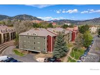 Exterior view of a multi-story apartment complex with balconies and ample parking, set against a mountain backdrop at 2802 Sundown Ln # 102, Boulder, CO 80303