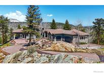 Stunning mountain home with a tile roof and stone accents, surrounded by beautiful landscaping and mature trees at 290 Skyhill Dr, Evergreen, CO 80439