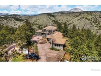 A luxurious multi-story home with a tile roof is nestled in a mountain setting and surrounded by lush trees at 290 Skyhill Dr, Evergreen, CO 80439