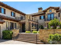 Beautiful stone home featuring a fountain, steps, and well-manicured greenery at 6851 Goldbranch Dr, Niwot, CO 80503