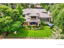 Expansive backyard with lush landscaping, patio seating, and meticulous lawn featuring mature trees offering shade at 7205 Rustic Trl, Boulder, CO 80301
